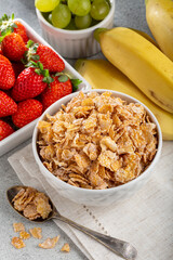 Corn flakes in the bowl with berries on the table.