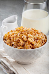 Corn flakes in bowl and glass of milk on table.