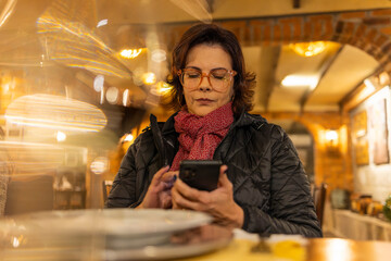 Beautiful red-haired woman accessing her cell phone in a cozy restaurant in Bento Gonçalves, RS, Brazil