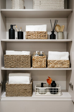 Bathroom cabinet with toilet paper rolls, white bath towels and cosmetics bottles