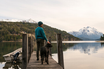 Obraz na płótnie Canvas Joven de vacaciones disfrutando junto a su perro de un paisaje único entre lagos y montañas en Patagonia. 