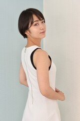 室内にてポーズをとる白いワンピースを着た若い女性のポートレート