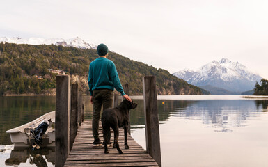 Joven disfrutando del paisaje junto a su mascota en un muelle de San Carlos de Bariloche,...