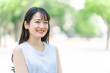 緑の中で笑う若い日本人女性（環境・美白・SDGs/笑顔）
