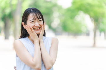 新緑の中で笑顔の日本人女性（小顔・嬉しい・楽しい）

