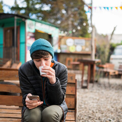 Joven disfrutando un rico café  mientras observa su teléfono  celular  en un paraje de comidas...