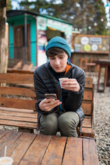 Obraz premium Joven disfrutando un delicioso café en un patio de comidas al aire libre durante un paseo por Bariloche. 