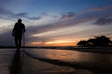 Fototapeta premium silhouette of a person walking on the beach at sunset