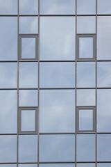 Glazed wall of a building with reflection of clouds in mirrored windows