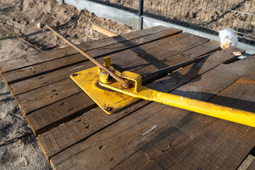 Wooden desk with steel rod bending machine at construction site. The armature bending machine...