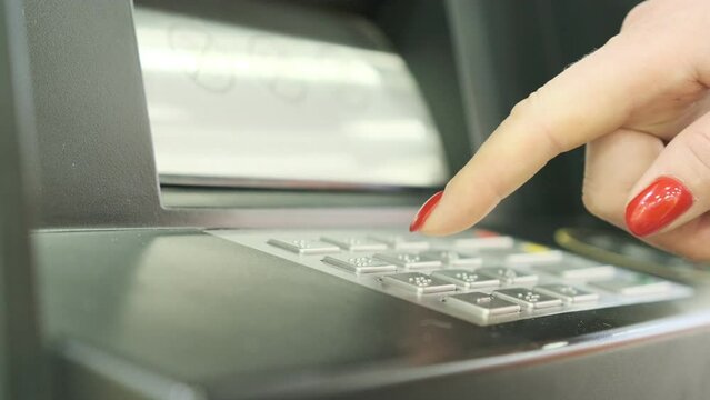 A young woman iusing an ATM machine to get money from her credit card.