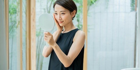 手鏡を持ち肌の調子を実感する美しい日本人女性