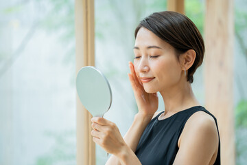 手鏡を持ち肌の調子を実感する美しい日本人女性