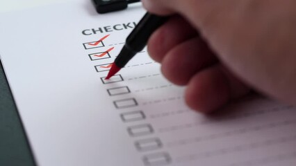 Checklist and To Do List Concept. Close-up businessman tick off or marking with red mark on checklist, checkbox, to do list box after completing task on white paper. Selective focus 4K resolution