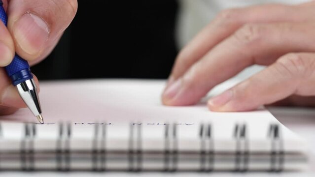Close up hand writing paper on notebook with blue pen to note, memo, list action plan at office or home desk, selective focus 4k resolution. Concept of write on paper, letter, pen, notepad, diary
