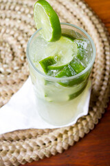 Caipirinha, caipiroska de limão e morango com gelo, gelada, em restaurante e guardanapo em baixo e sobre uma madeira