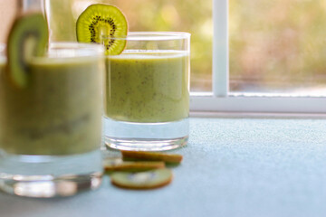 kiwi smoothie in a glass on blue background, blurred background