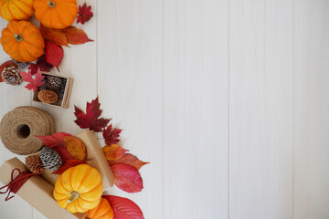 Autumn greeting background. Colorful autumn leaves, pumpkin and gift box composition on white wooden background. Thanksgiving, Fall greeting, autumn festival background and Banner design elements.