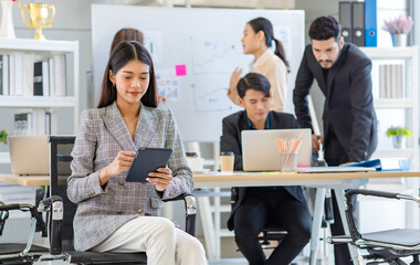 Portrait shot Asian young successful friendly businesswoman in formal suit sitting smiling holding tablet while male businessman and female colleagues working brainstorming together in meeting room