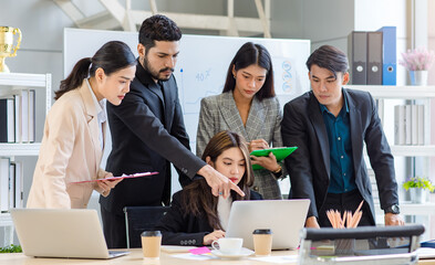 Multicultural multinational millennial Asian female businesswomen Indian male businessman boss in formal suit helping working brainstorming together with laptop computer in conference meeting room