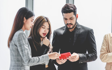 Closeup shot of two young millennial Asian doubtful female businesswomen in formal suit standing asking business solution ideas via tablet computer from Indian bearded male businessman manager mentor