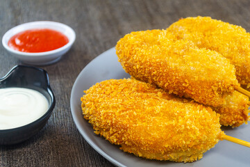 Mozarella Corndog served with mayonnaise, chili sauce and parsley. It has a savory taste and is cooked by frying