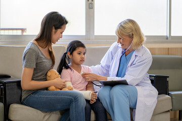 Obraz premium Pediatrician doctor examining little asian girl with a broken arm wearing a cast at hospital