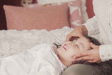 mother pretend play facial massage with her daughter in bed, family lifestyle wellness concept