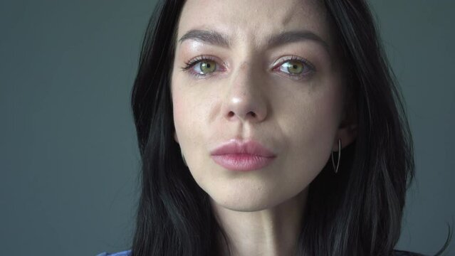 Young crying woman with green eyes in studio portrait.  tears with emotional expression