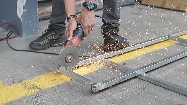 Captura de la mano de la sierra circular el&eacute;ctrica cortando la superficie del metal con chispas. Primer plano
