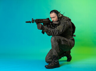 soldier in the studio on a green background with colored light. a man in military uniform with a gun, rifle or machine gun. military. airball player