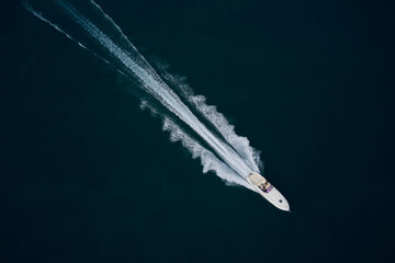 Fast moving white boat with people aerial view. Super speed white boat fast movement on dark water...