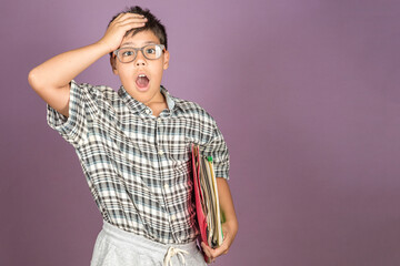 Cute ten year-old Latin student in eyeglasses holding folders and papers with surprised gesture and...