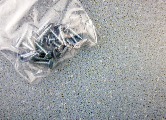 A plastic bag with a set of self-tapping screws for a carpenter or repair. Metal screws in plastic packaging on the background for copying or pasting text.