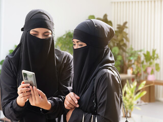 Two pretty Muslim women looking at smart phone checking photos