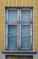 Fototapeta na wymiar Old window with metal corners and worn out cracked peeling paint of wooden frame