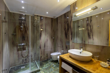 Interior of a luxury hotel bathroom with marble walls and glass shower cabin