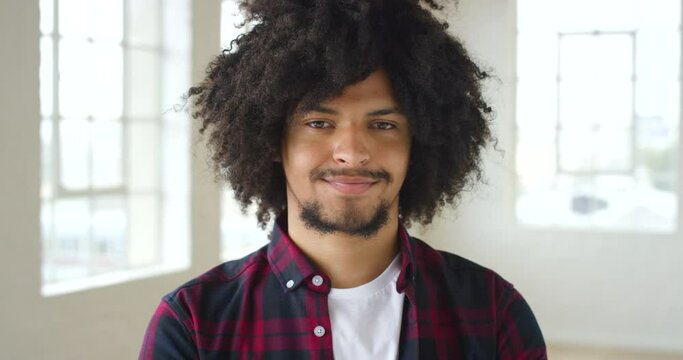 A young black confident male with an afro taking a deep breath while standing in his home. Portrait of an attractive and trendy African man with cool curly hair inside his house or home