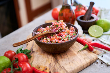 freshly made salsa dip sauce - chopped garlic, tomatoes and onion in wooden bowl