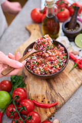 making salsa dip sauce - woman mixing chopped ingredients in wooden bowl