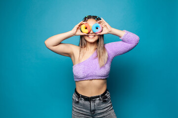 Stylish beautiful woman holding donut sweet snack delicious pastry in her hands on blue banner...
