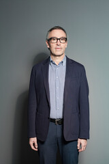 Fototapeta premium Intelligence mature businessman standing on grey background