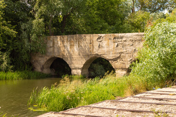 Fototapeta na wymiar Old abandoned stone bridge across the river in the Lipetsk region