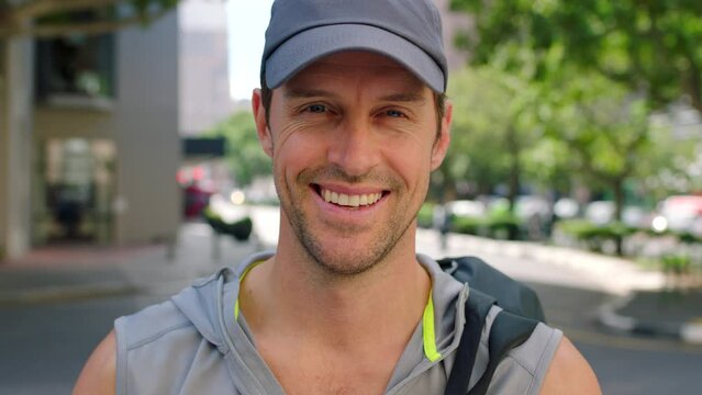 Portrait of a sporty young man wearing a cap and smiling while out in the urban city. Fit man looking positive and ready to exercise at the gym. Feeling good and living an active lifestyle