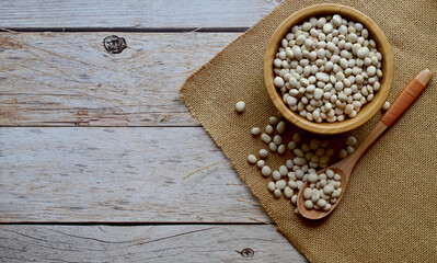 Top Views of Dried White Kidney Beans in a wooden cup Some are in wooden spoons and sackcloth on the wooden background, Healthy Food Concept.