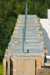 A reinforced concrete beam, steel bars and a wooden formwork on the first floor of a house under construction, walls made of autoclaved aerated concrete