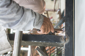 worker  welds the steel structure of the roof at the construction site.