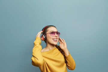 Portrait of happy girl listening music with wireless headphones from a smartphone. Woman uses wireless earphones
