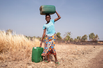 Cute little West African girl with water containers; symbol for the lack of water infrastructure in...