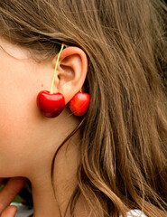Earrings from yellow-red cherries on the girl's ear